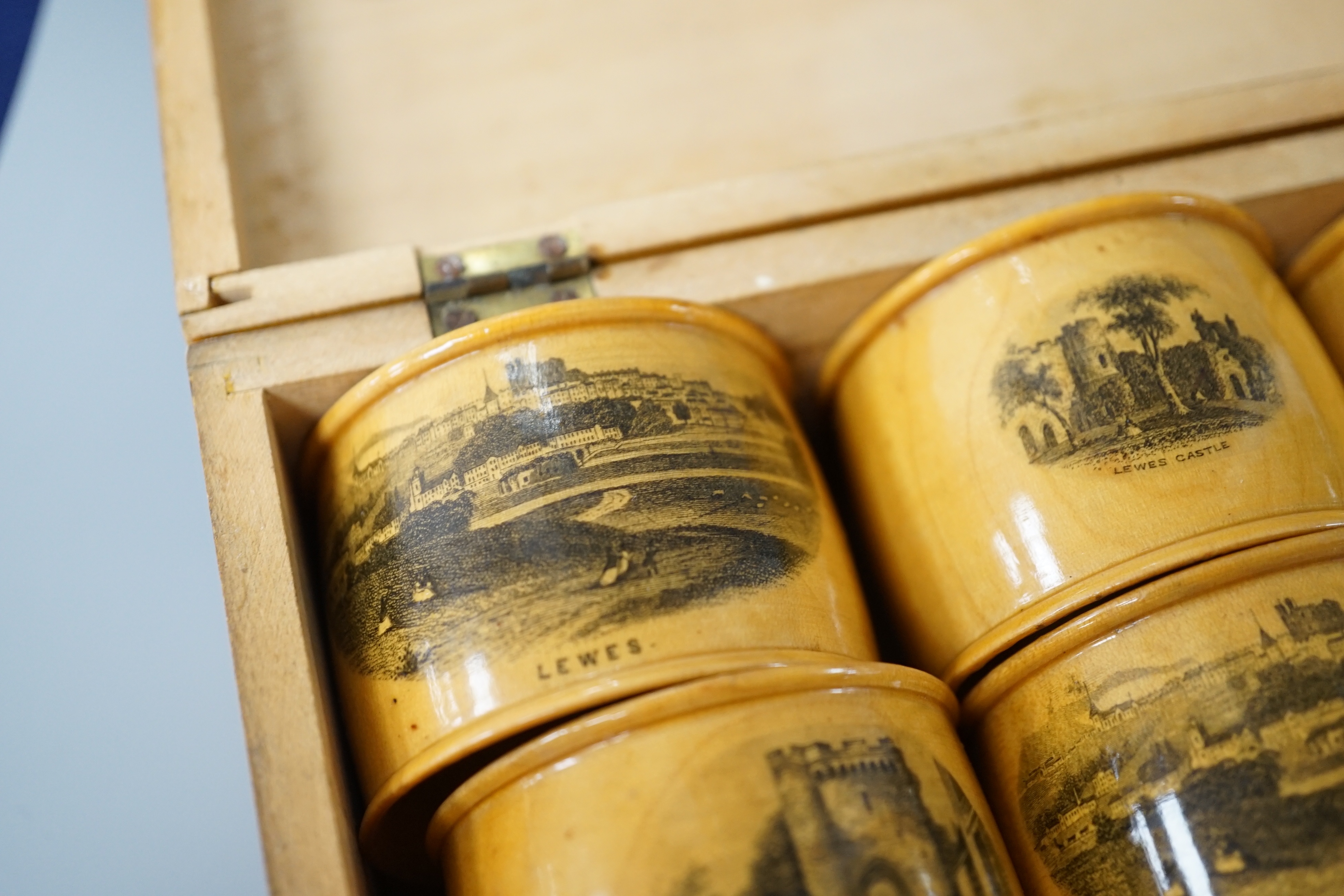A set of 6 late 19th century mauchline ware napkin rings decorated with scenes of Lewes, housed in matching box. 18cm